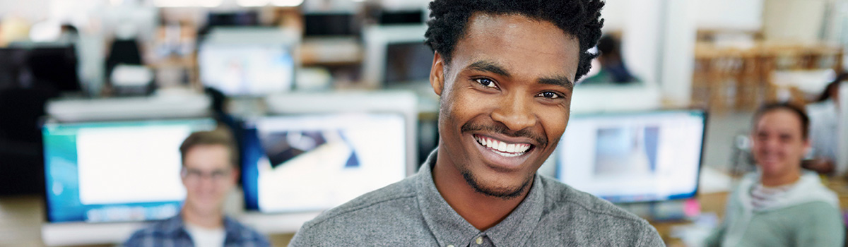 smiling young man with co-workers in background