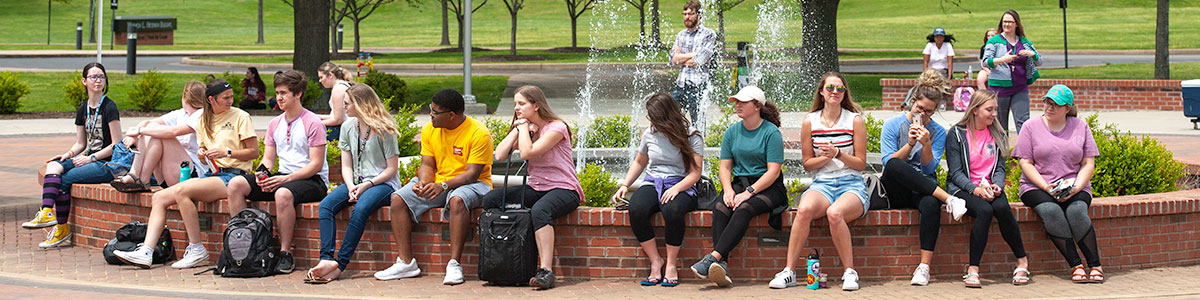 students sitting by the fountain