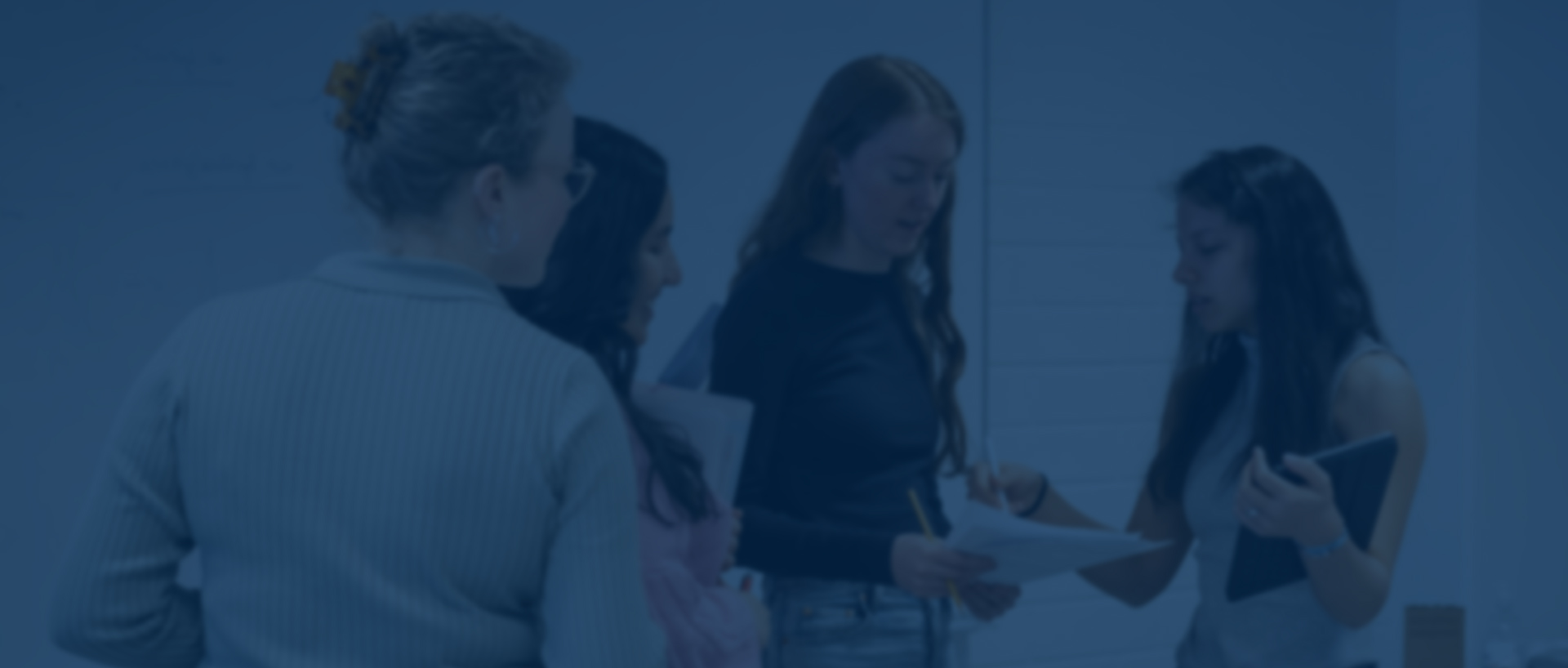 students gathered in a class looking at a paper