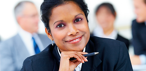 A woman holding a pen and smiling at the camera