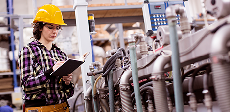 A woman with a hard hat standing near industrial machinery