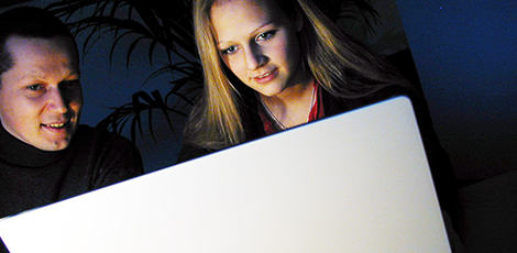 A man and a woman standing in front of a large laptop