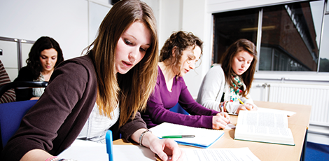 A group of students at a table writing in their notebooks