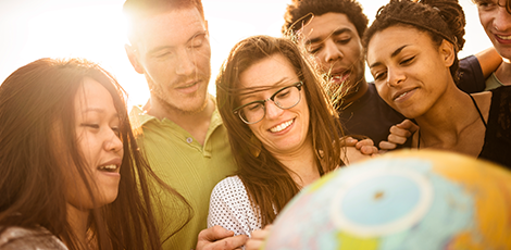 A group of people standing over a globe while smiling