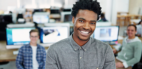 A man smiling at the camera while two other smiling people are blurred out behind him