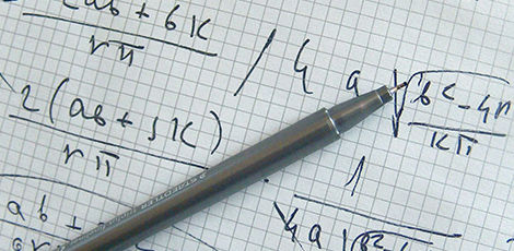 A pen laid on a piece of paper with mathematical equations.