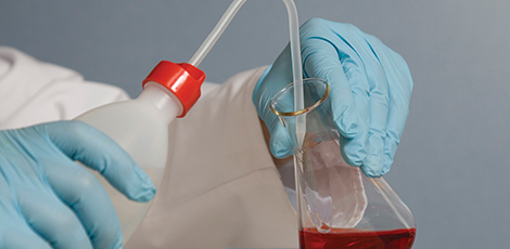 someone filling a beaker with a red liquid