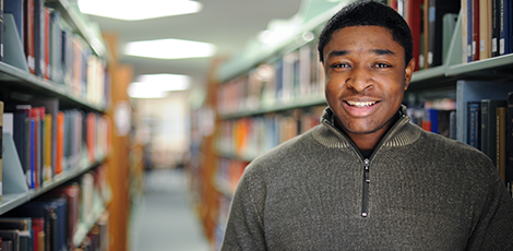 A man smiling at the camera while in a library