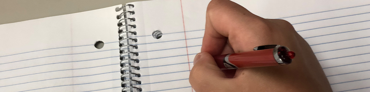 hand with pen writing in notebook