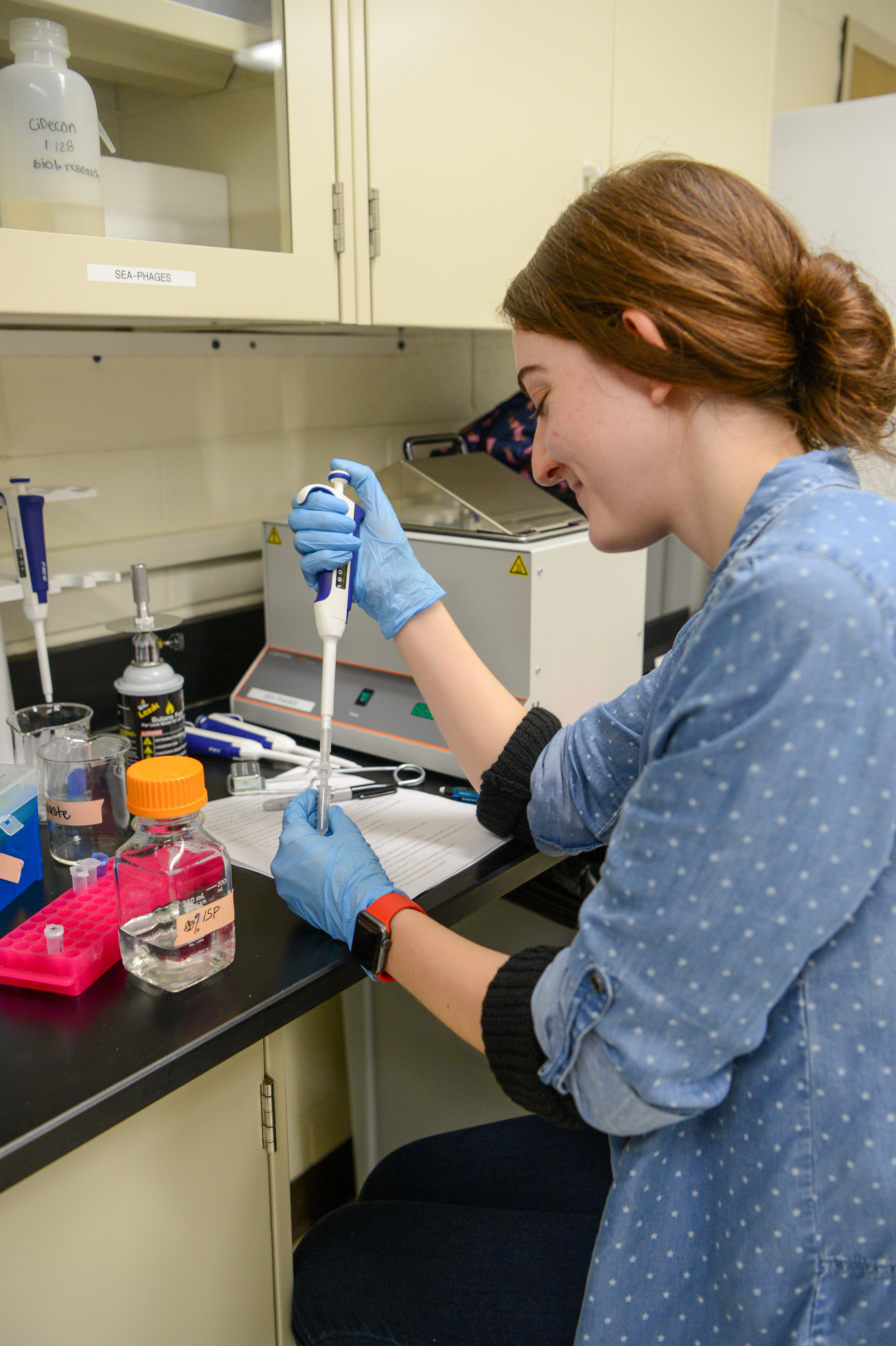 Tessa wears a blue shirt and works in a lab