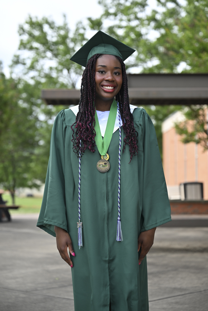 A person smiles while wearing a cap and gown. 