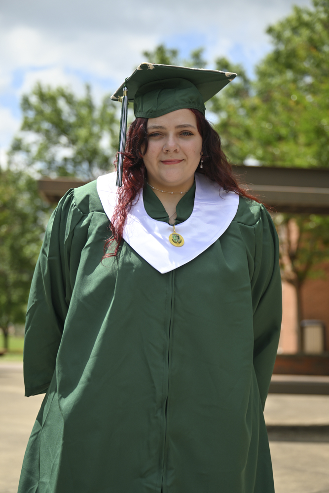 A person smiles wearing a cap and gown.