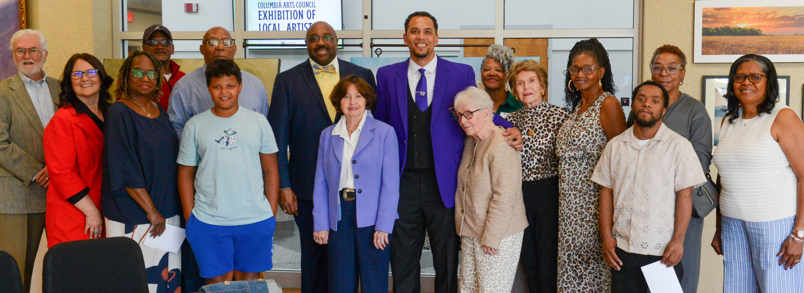 A large group of standing people smile for photo.