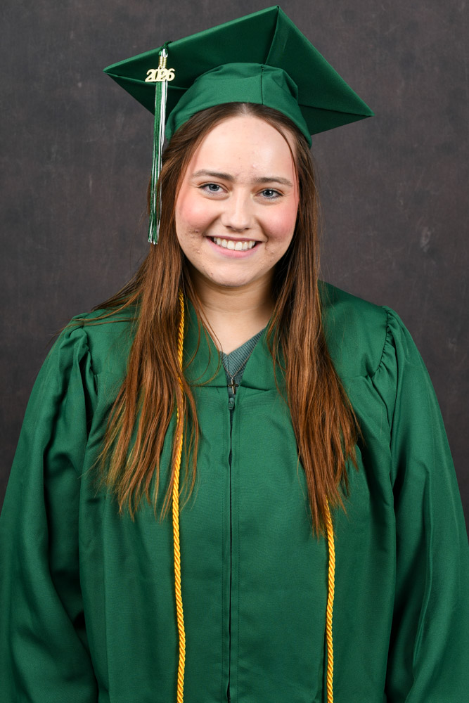 A person stands outside in a cap and gown.