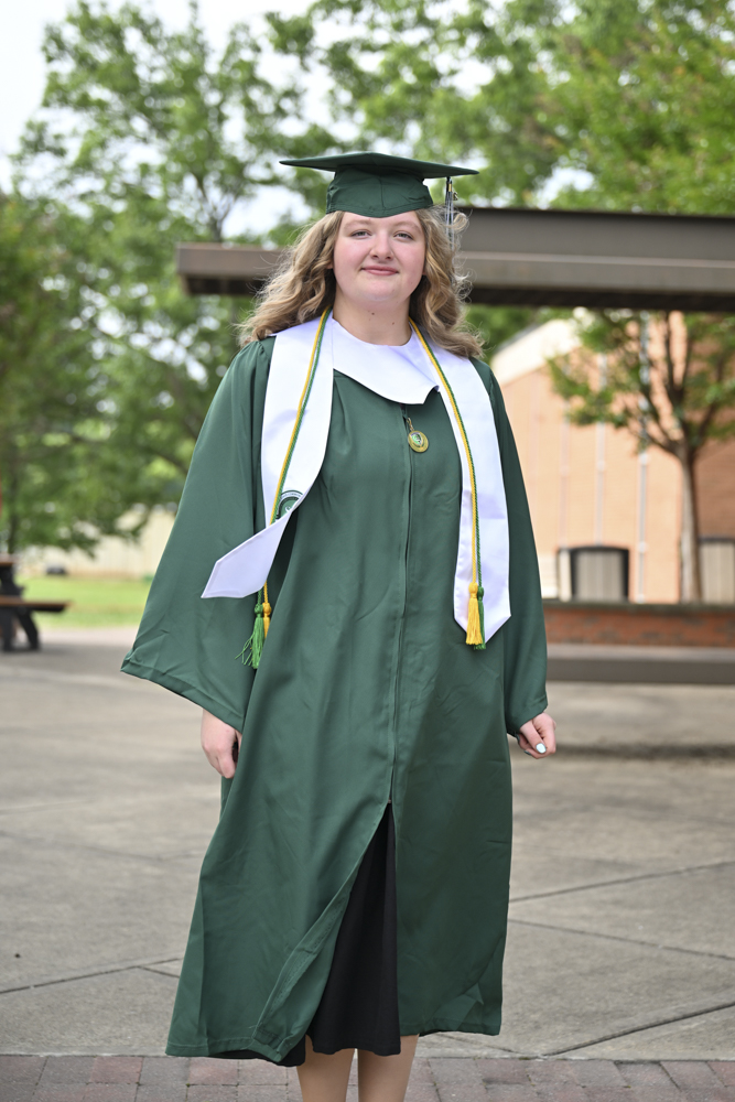 A person stands outside in a cap and gown.