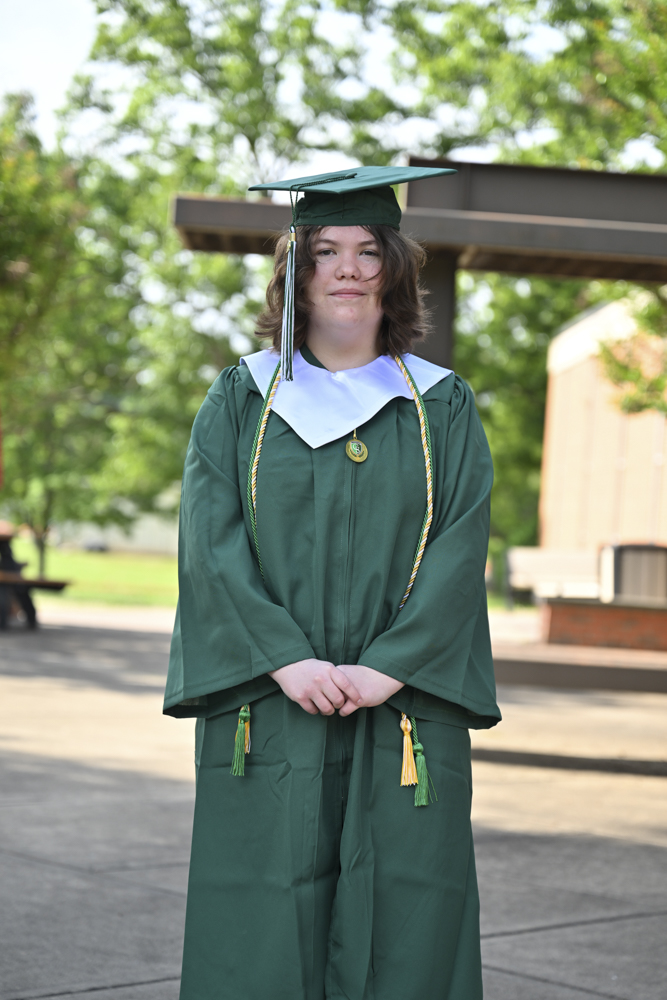 A person stands outside in a cap and gown.
