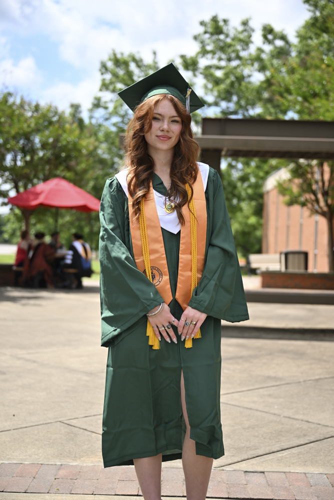 A person stands outside in a cap and gown.