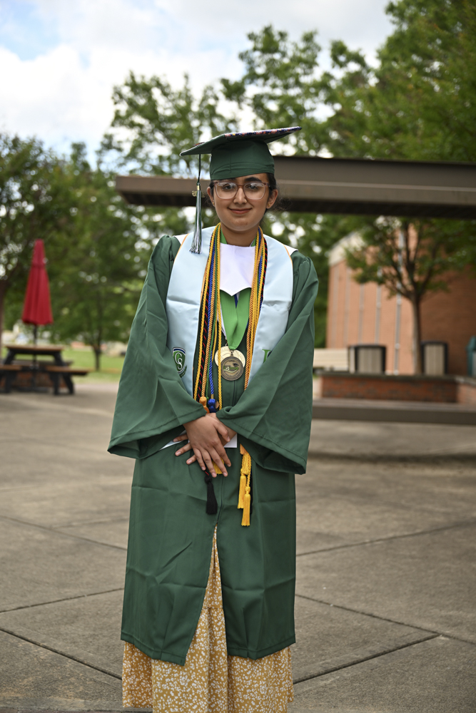A person stands outside in a cap and gown.