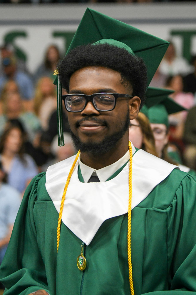 A person stands outside in a cap and gown.