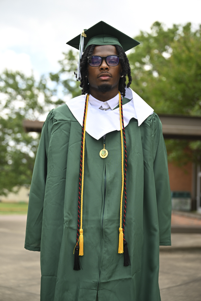 A person stands outside in a cap and gown.