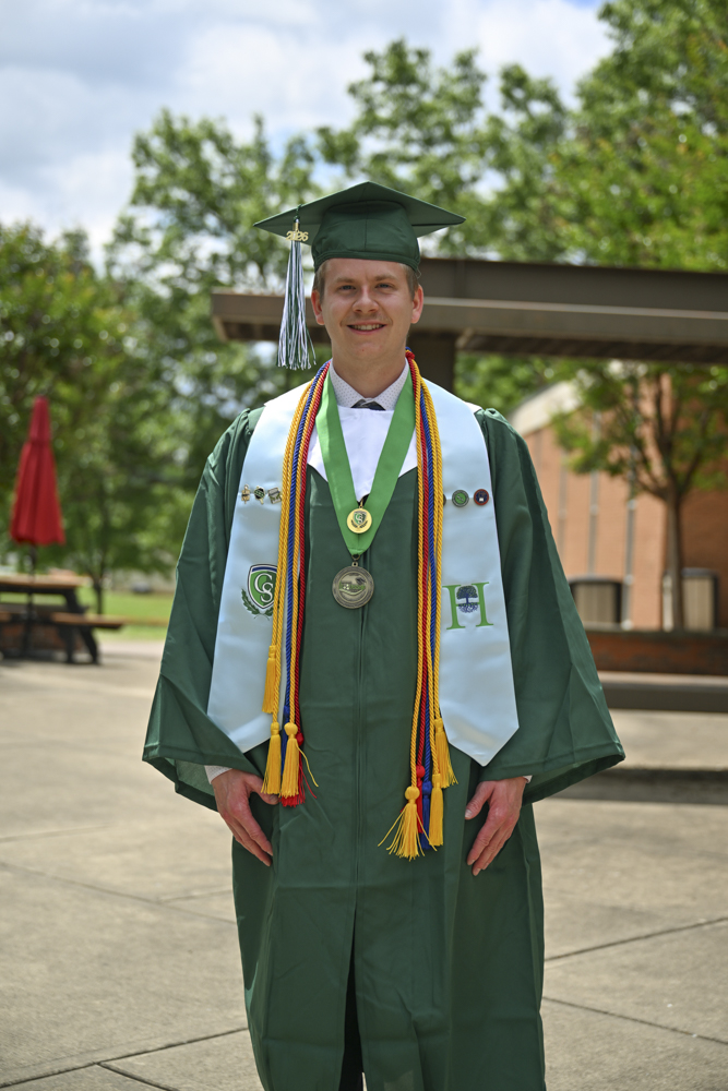 A person stands outside in a cap and gown.