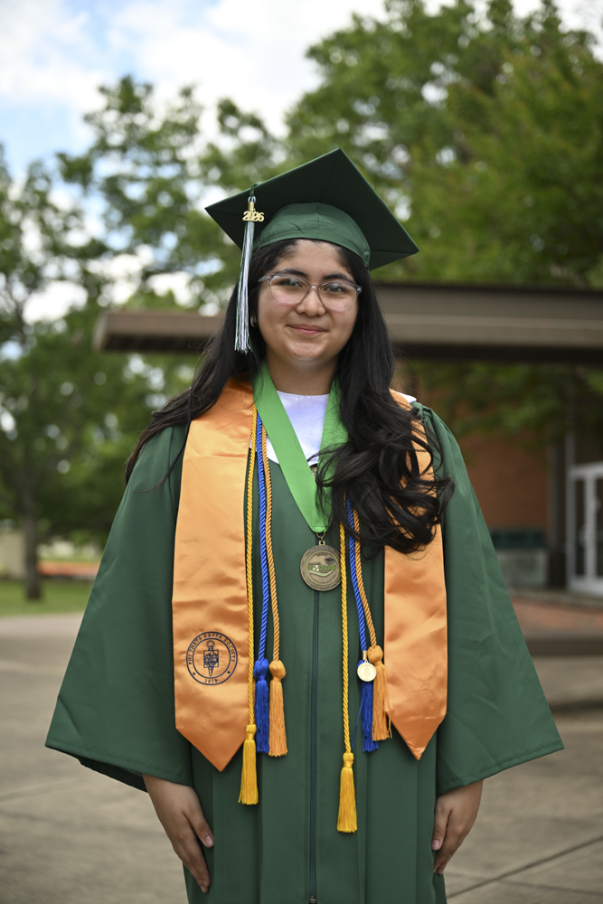 A person stands outside in a cap and gown.