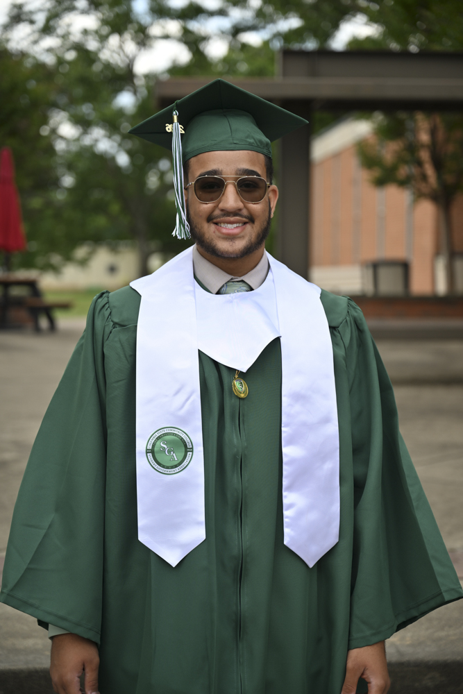 A person stands outside in a cap and gown.