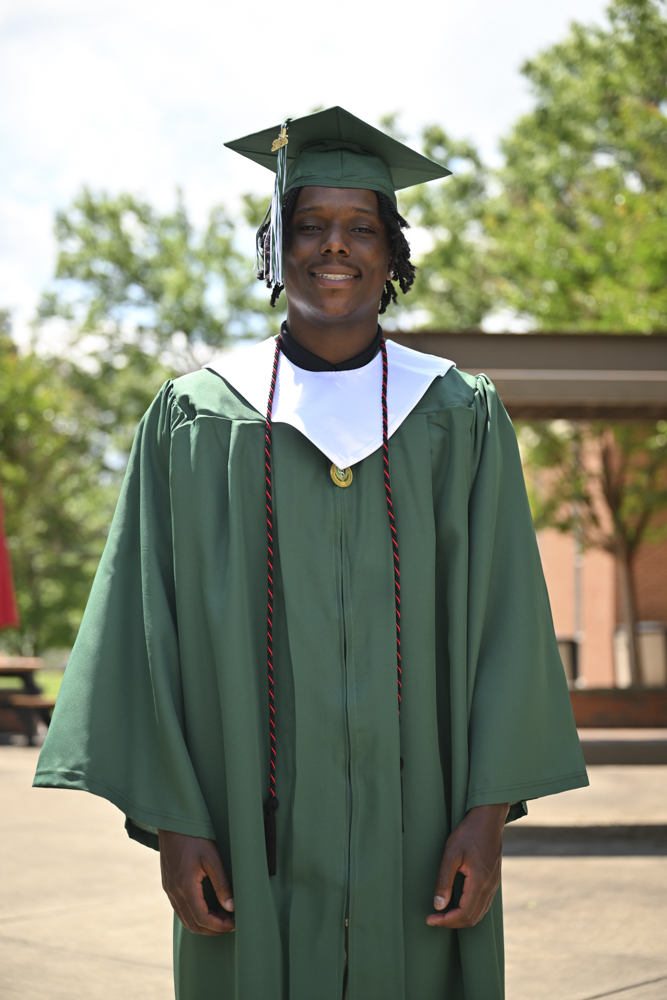 A person stands outside in a cap and gown.