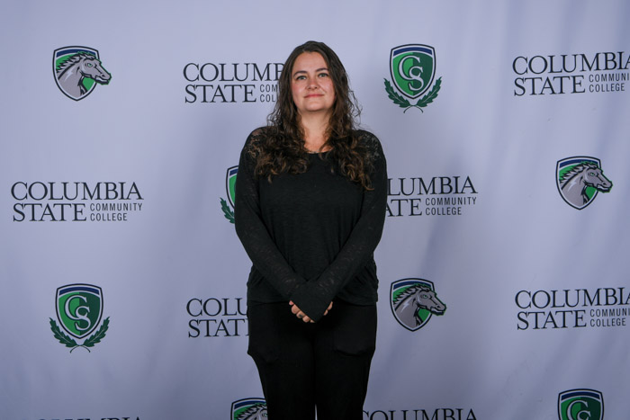 A person stands in front of a white background. 