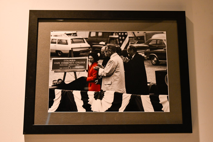 A photos shows a framed photograph of Lady Bird Johnson and President Lyndon B. Johnson unveiling the first Columbia State sign at the 1967 dedication event.