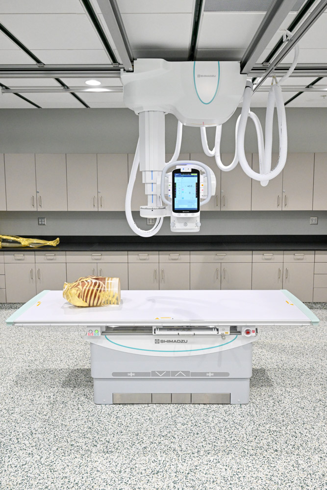 An anatomical manikin lays on an X-ray table in a classroom.