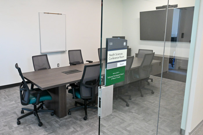 A conference room has a table, chairs and a computer.