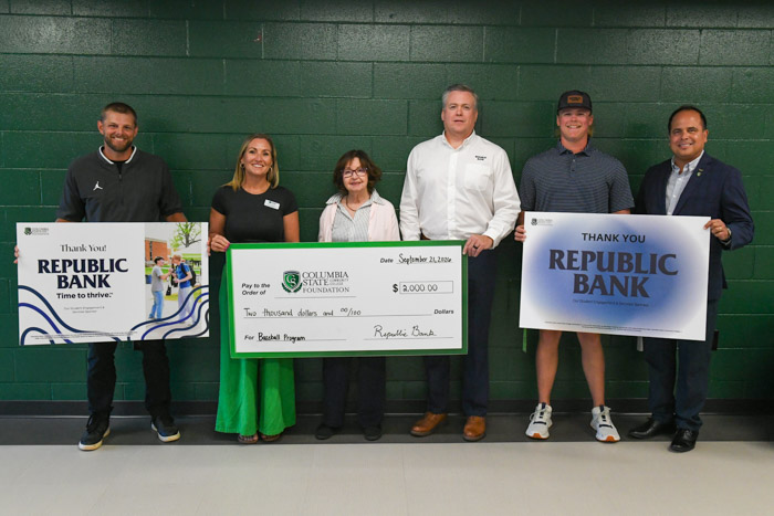 Six people hold a large signed check and Republic Bank signs while posing for a photo.
