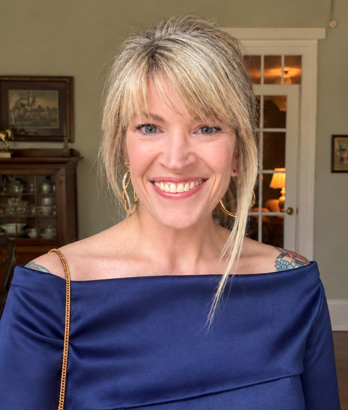 A person wearing a blue dress smiles for a close-up photo.