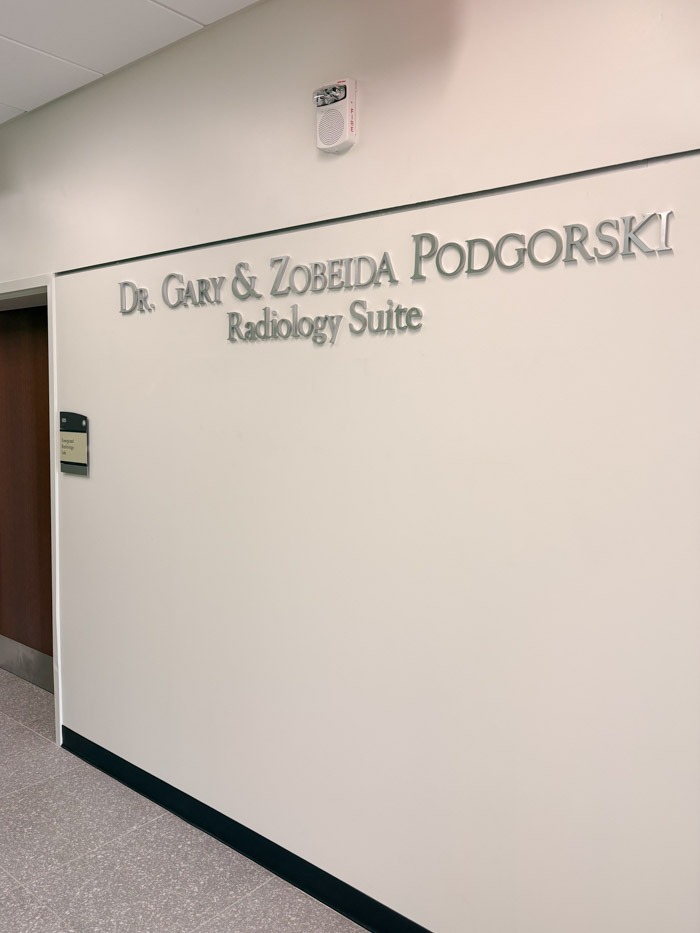 A white wall in a hallway says "Dr. Gary and Zobeida Podgorski Radiology Suite."