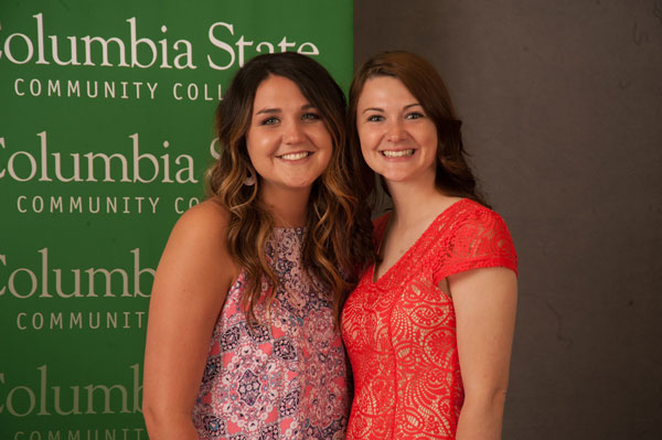 Two brunettes smile in front of CSCC background 