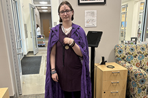 Student in black dress with purple robe